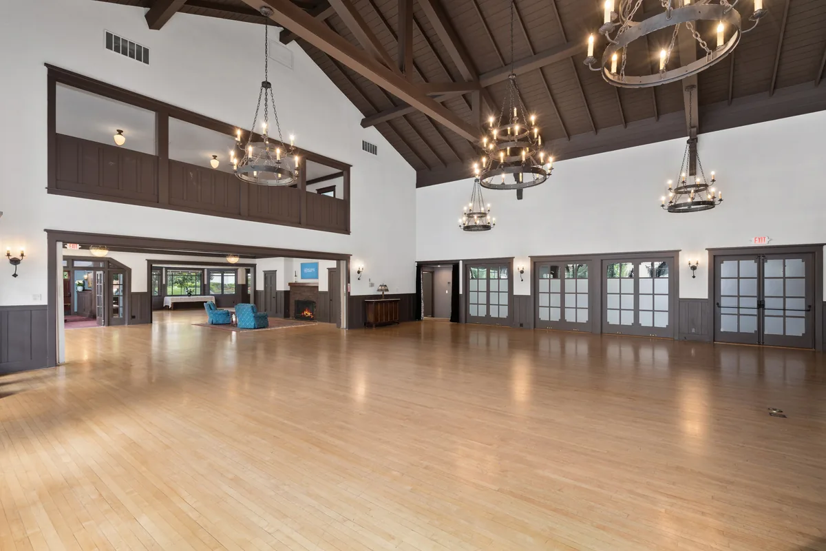 The Clubhouse main hall in a wide view, open floor set for a banquet with original wood trim and tall windows
